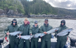 Alaska Family Vacation: A family of anglers proudly holding large silver salmon at the dock at Screamin' Reels Lodge.