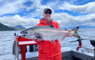 Man holding up fish on boat during an Alaska fishing vacation